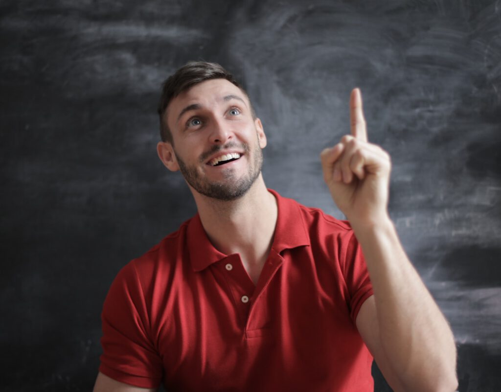 Man in red shirt is pointing his finger up